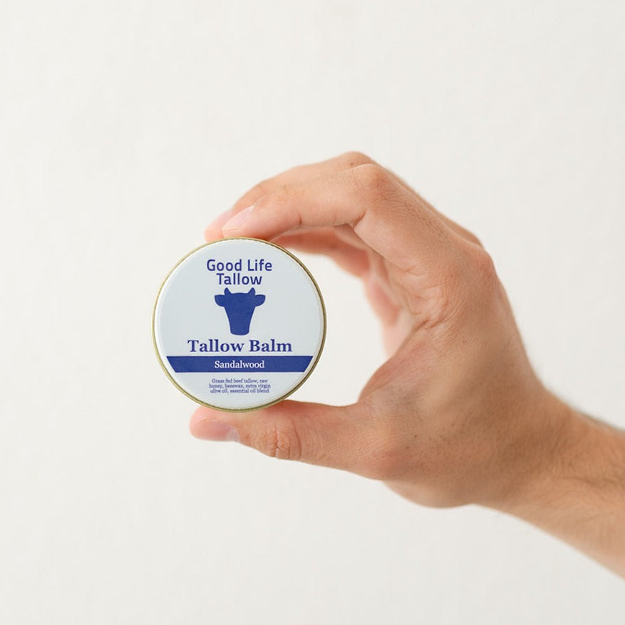 man hand holding up a jar of tallow balm showing the ingredients