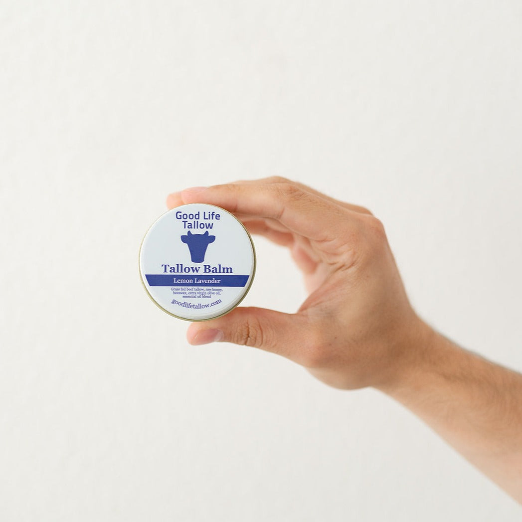 Male hand holding lemon lavender tallow balm showcasing the ingredients of grass fed beef tallow, raw honey, beeswax, olive oil and essential oil blends