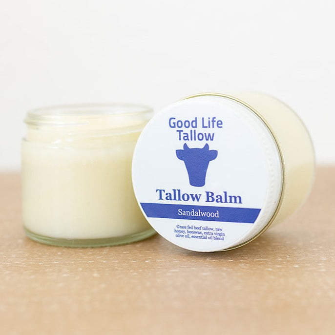 A display jar of tallow balm showcasing the ingredients or grass fed beef tallow, raw honey, beeswax, extra virgin olive oil, and essential oils